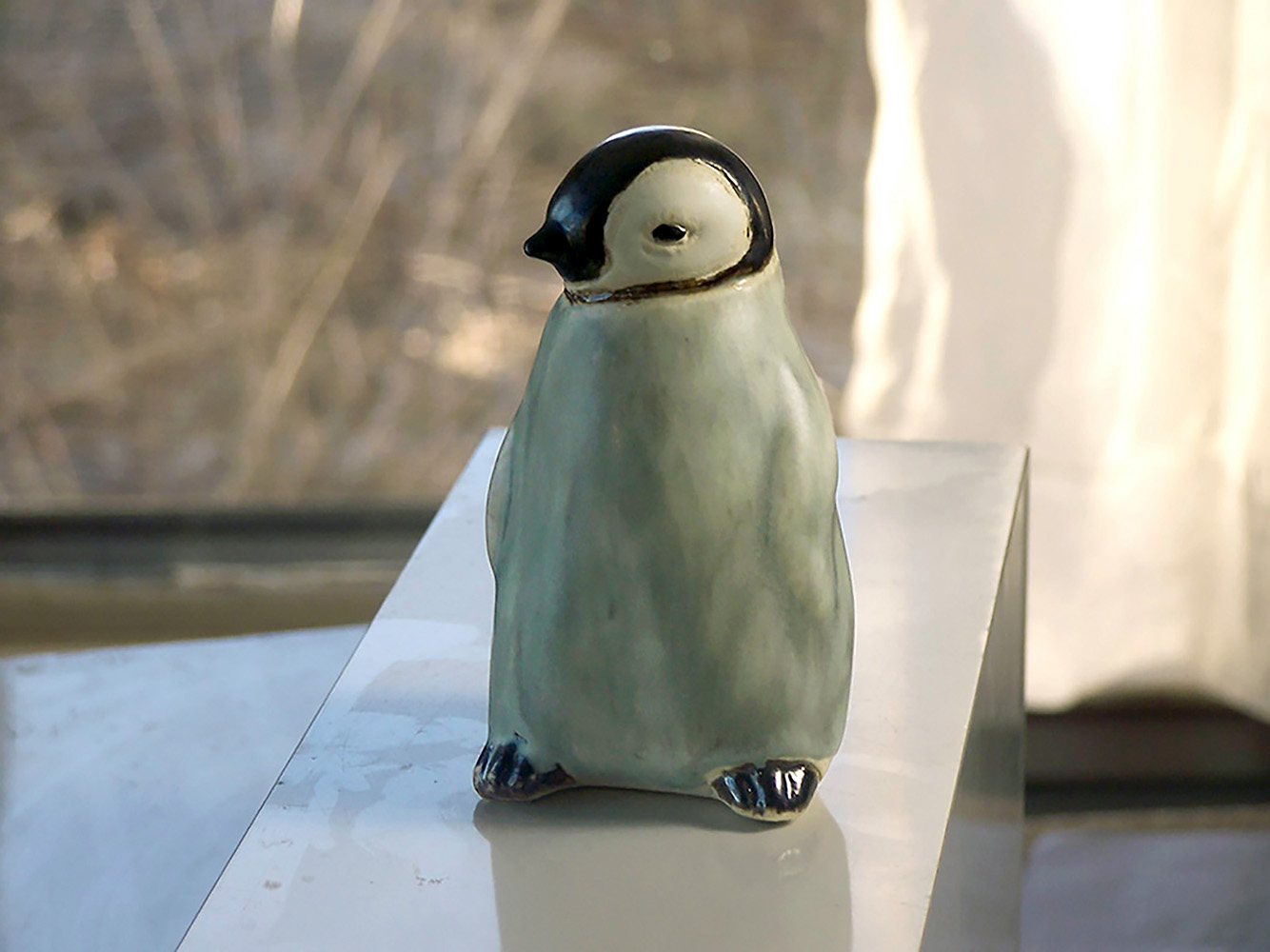 Baby Penguin Sculpture, 5 inches tall, Gray ceramic decorating color flows down the form creating variations in tone. A glossy ebony contrasts with the white matte glaze around the eyes. The Ceramic Baby Penguin is slip-cast in white stoneware and hand-crafted by American artisans,